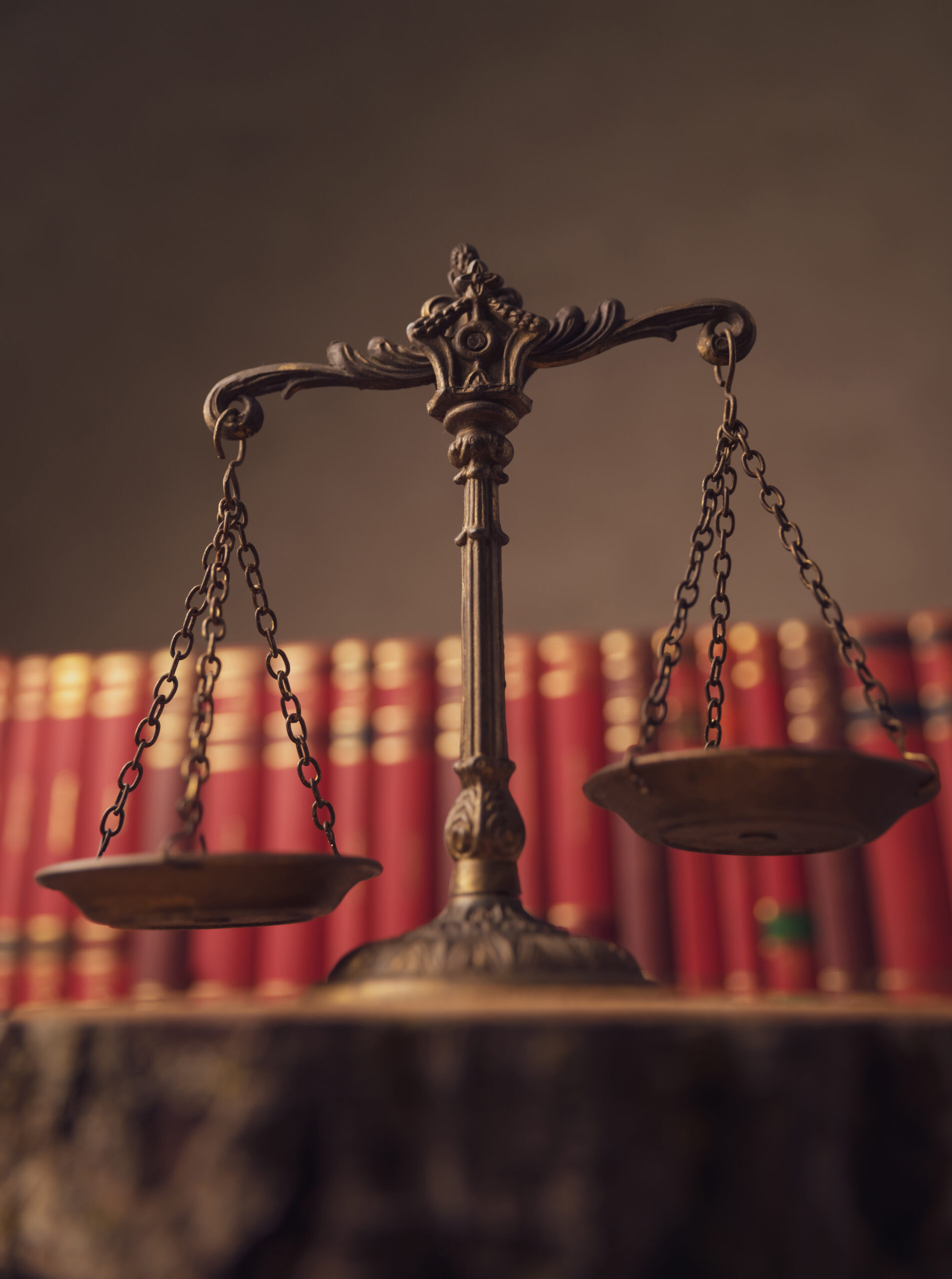 Conceito de justiça e direito representado por balança de bronze diante de livros jurídicos.